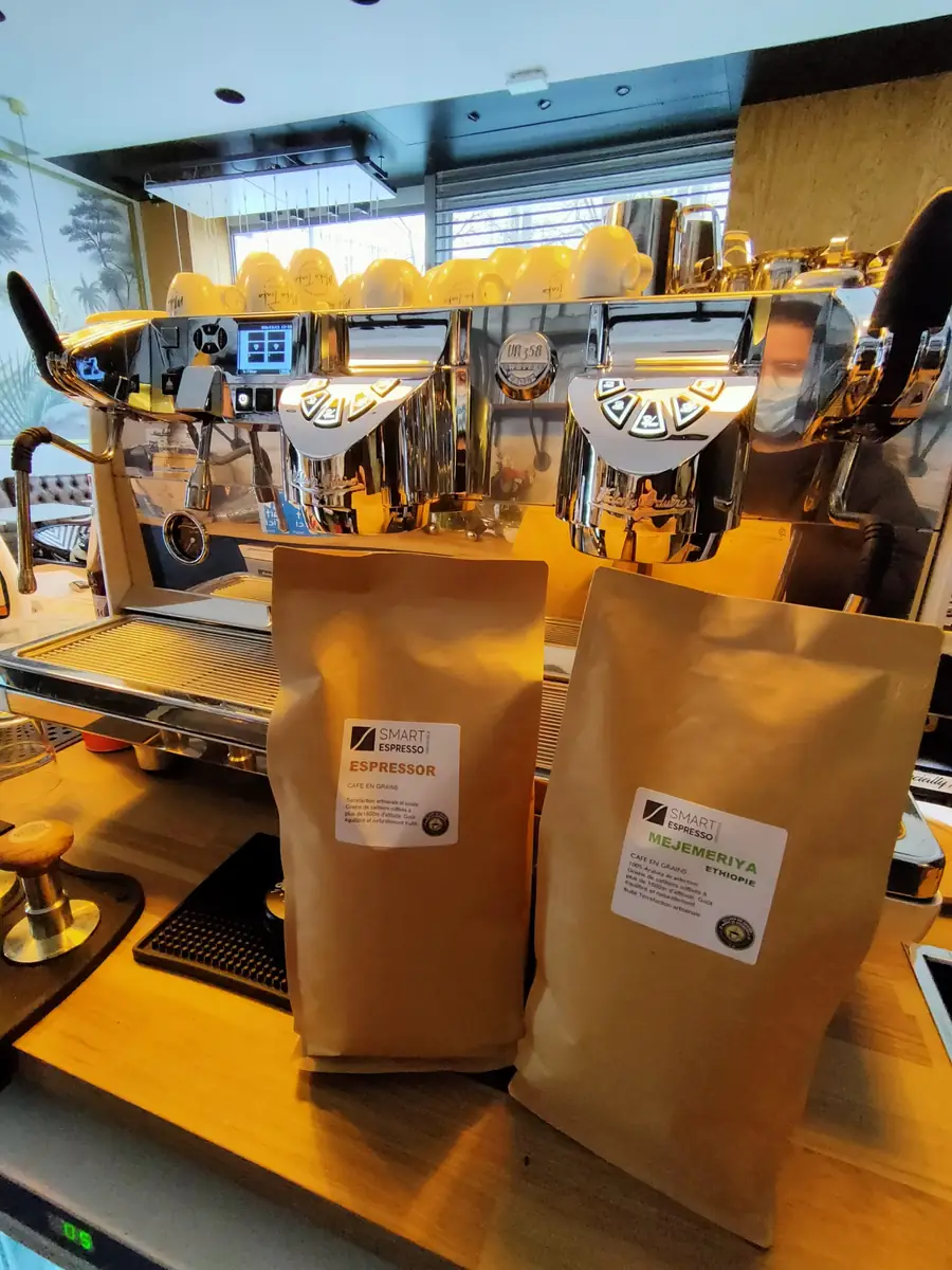 Sachets de café en grains Smart Espresso devant une machine expresso